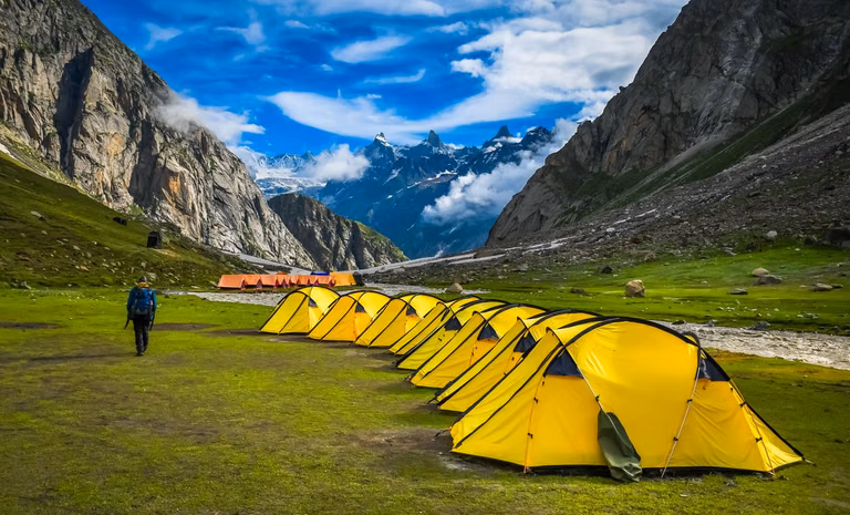 Camping tents in Sonmarg meadow with snow-capped mountains in background