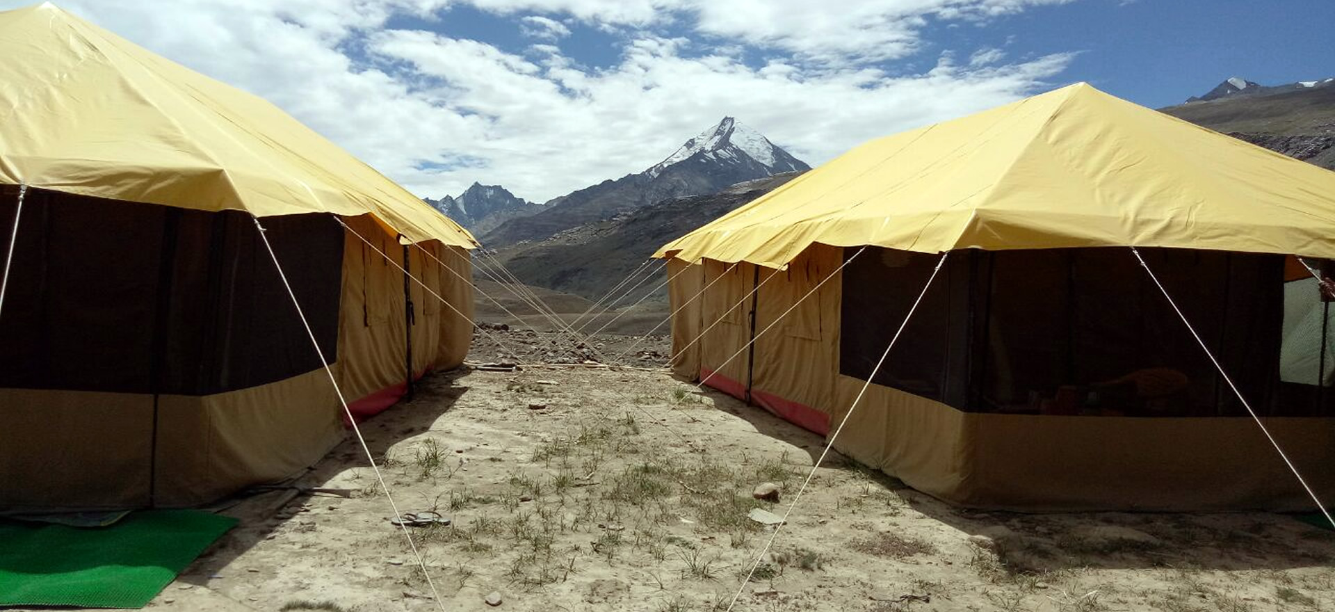 Tents camping beside Chandratal Lake with snow-capped mountains in background