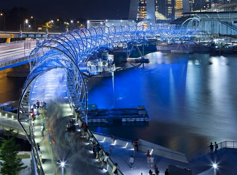 Evening crowd and skyline reflections near Helix Bridge