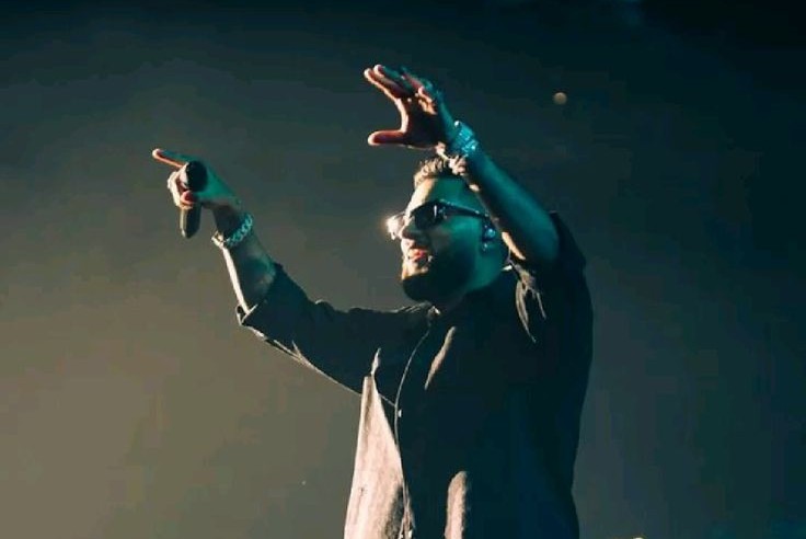 Karan Aujla on stage with band members performing with dramatic lighting effects