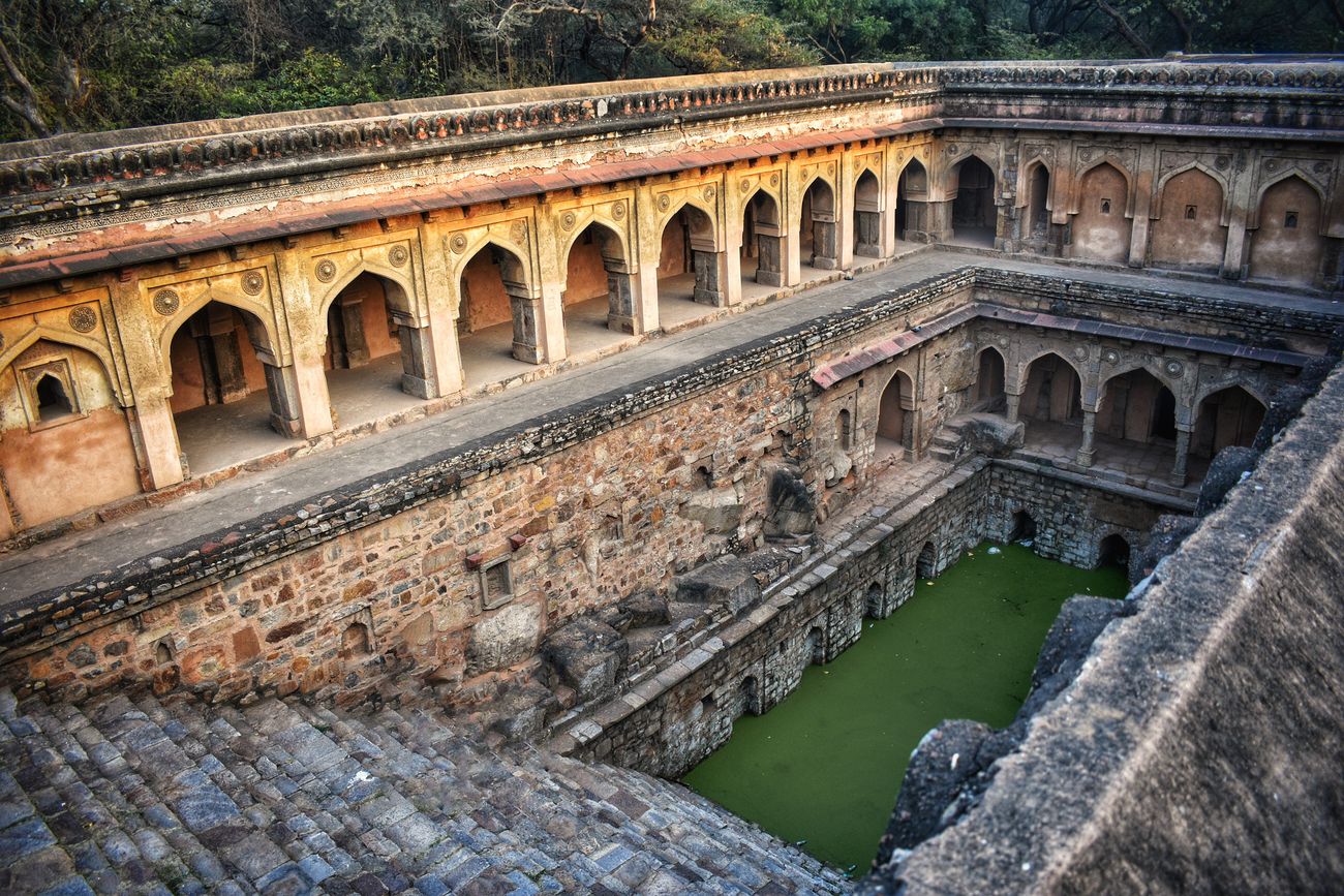 Historical structures and walking paths inside Mehrauli Archaeological Park in Delhi
