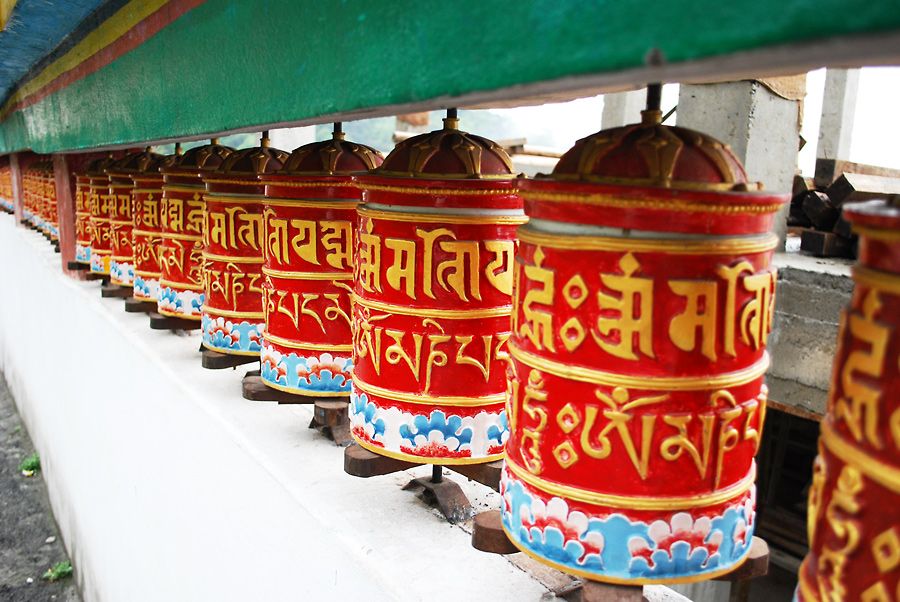 Buddhist prayer wheels at monastery with mountains backdrop