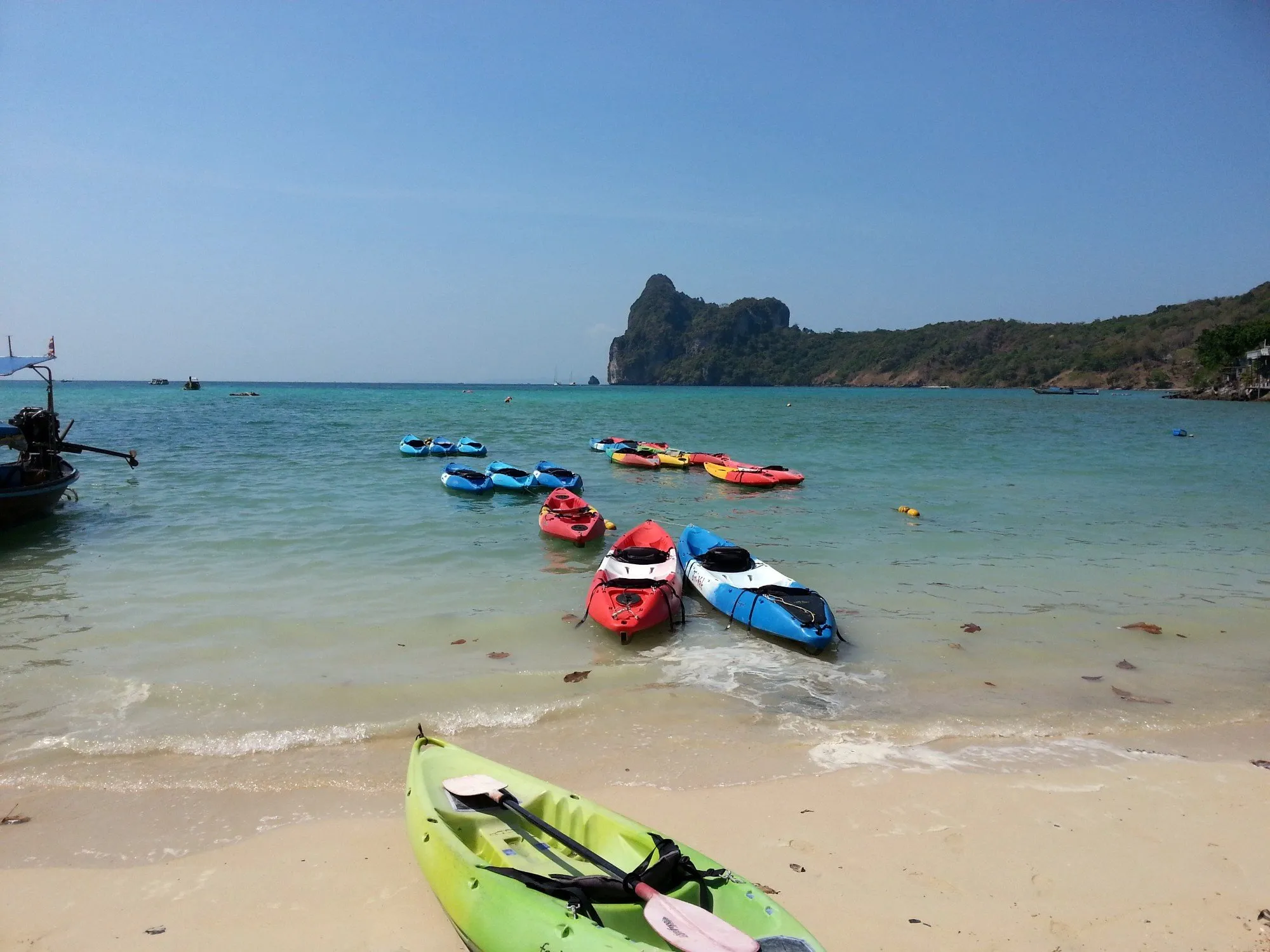 Kayakers paddling through crystal clear waters near limestone cliffs