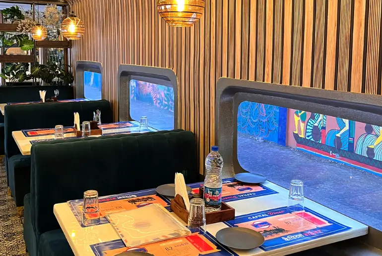 Family dining inside train coach style restaurant in Delhi