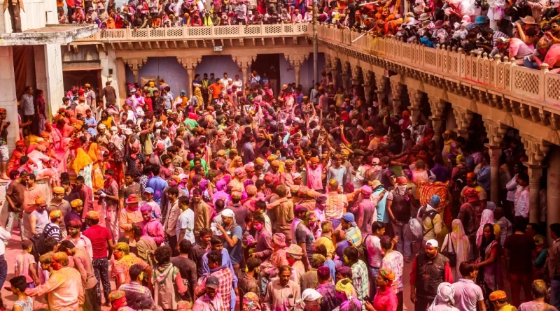Devotees playing Holi at Pushkar Lake ghats with temple in background
