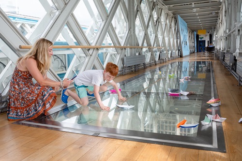 Visitors walking on Tower Bridge glass floor above traffic lanes