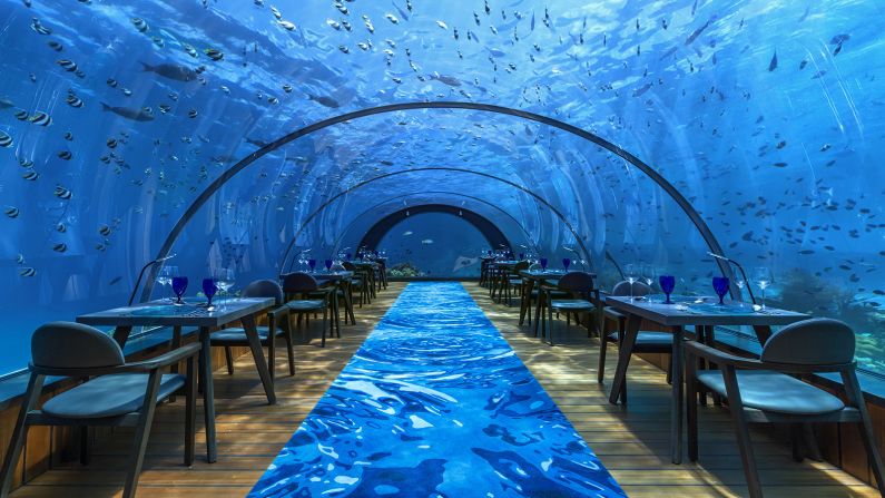 All glass undersea dining chamber with reef fish in Maldives