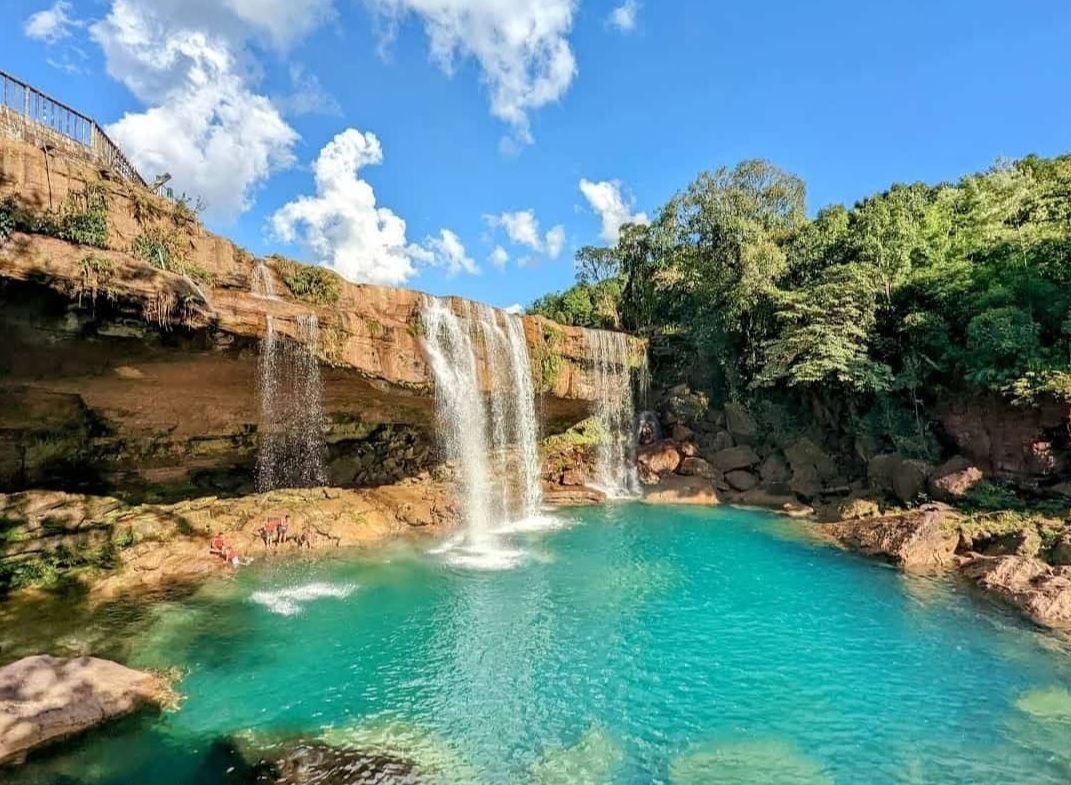 Photographer capturing long exposure shot of Wah Kaba Falls with tripod