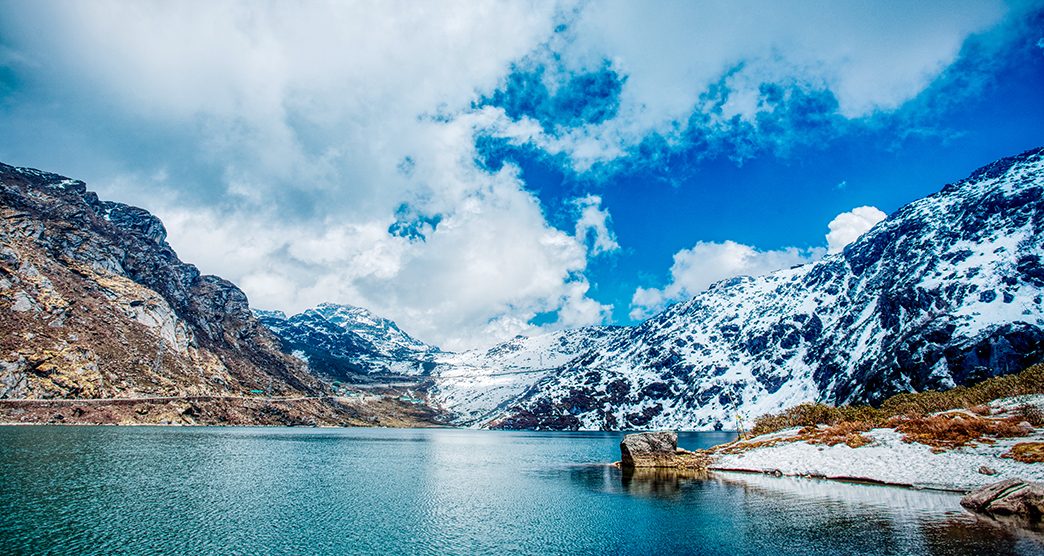 Panoramic view of Tsomgo Lake with yaks grazing on the banks